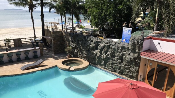 A swimming pool with a hot tub, lounge chairs, and a red umbrella. - Out Back (Olongapo)