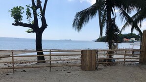 A beach with a bamboo fence, palm trees, and a view of the sea. - Out Back (Olongapo)