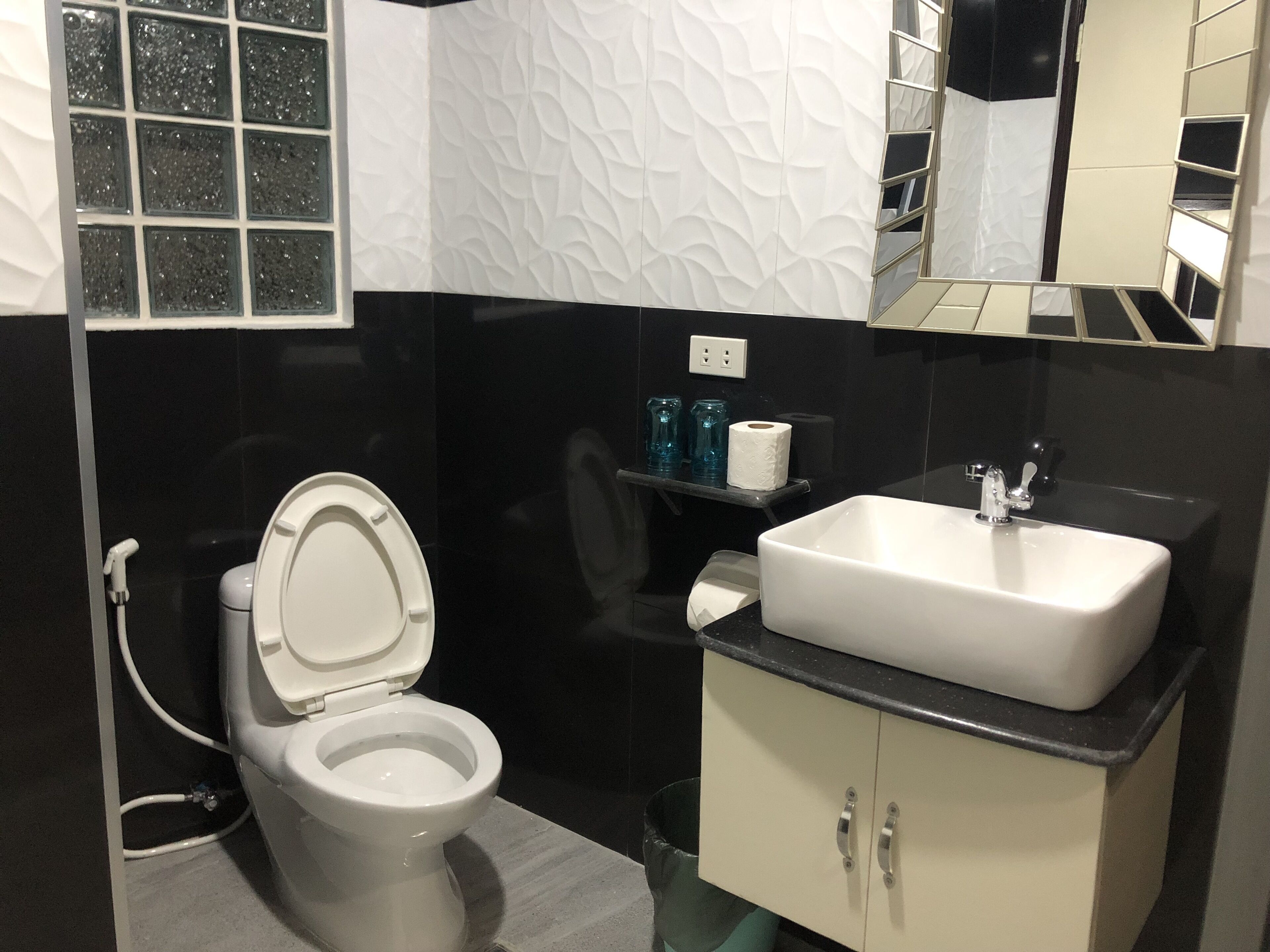 Een badkamer met toilet, wastafel en spiegel.