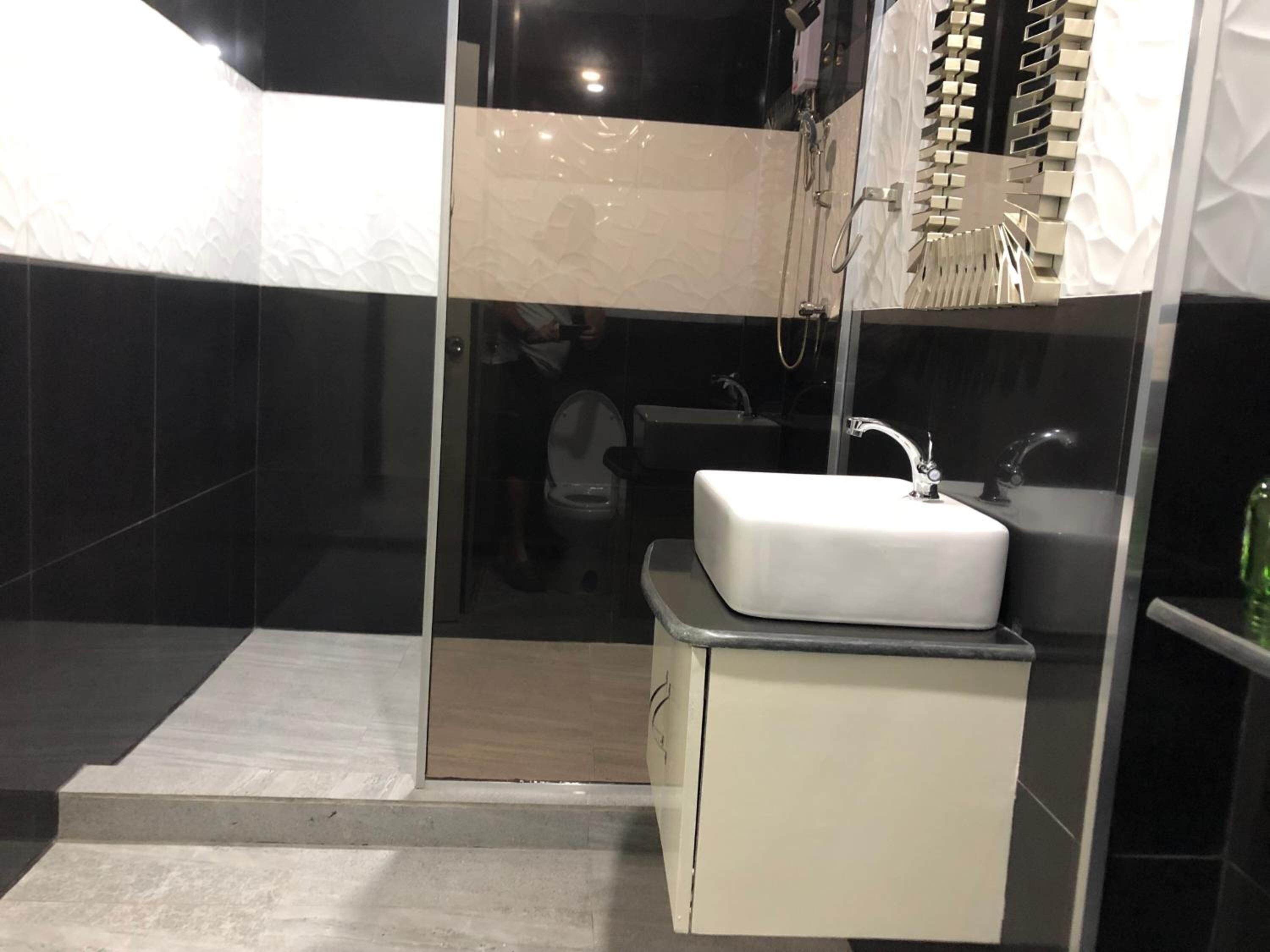 A modern bathroom with a glass shower enclosure, a white sink, and a vanity with a mirror.