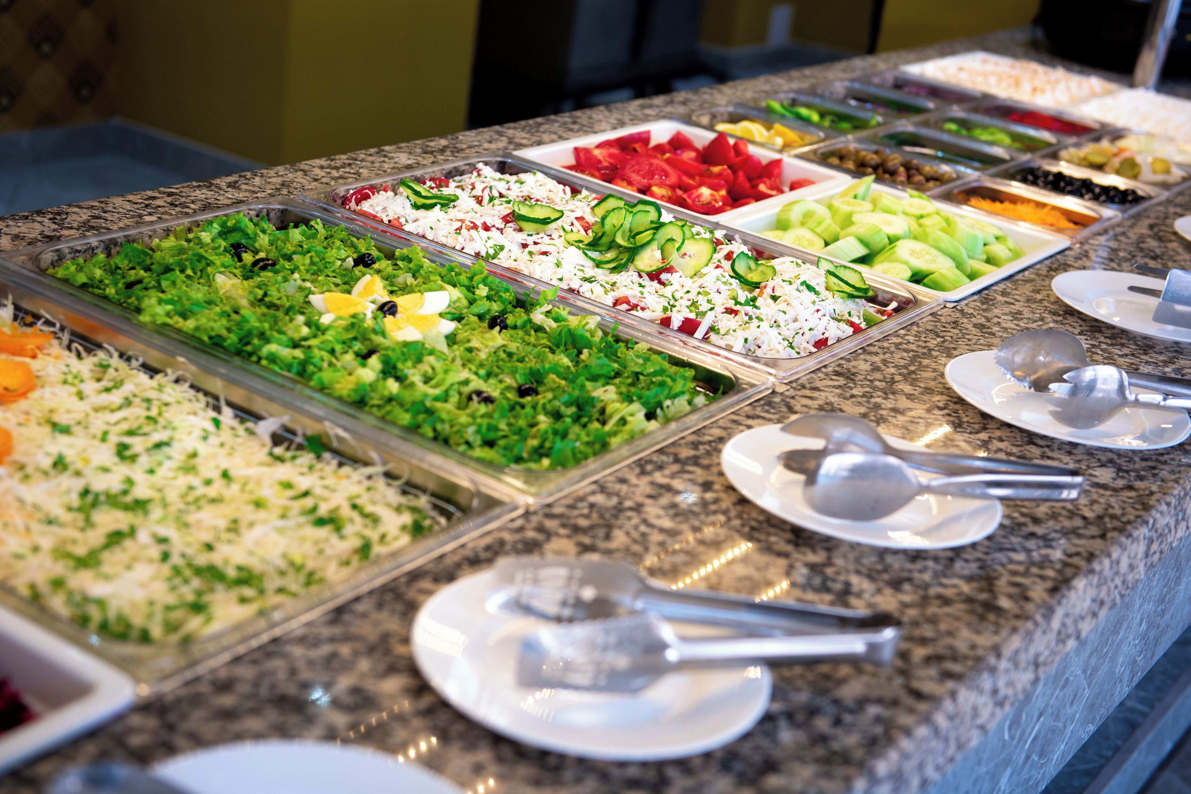 Un buffet proposant une variété de plats, notamment des salades, des fruits et des légumes.