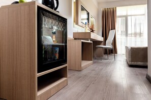 Habitación de hotel moderna con una televisión de pantalla plana grande, un mueble de madera, un escritorio, una silla y una cama.
