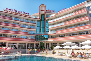 Un hotel de varios pisos con balcones, piscina y tumbonas.