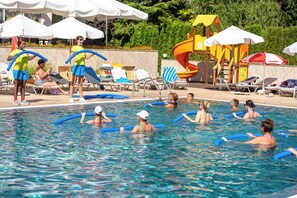 A swimming pool with lounge chairs and umbrellas, surrounded by greenery. - Maria Palace (Nessebar)