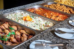 A buffet with various dishes including rice, chicken, and a red curry.