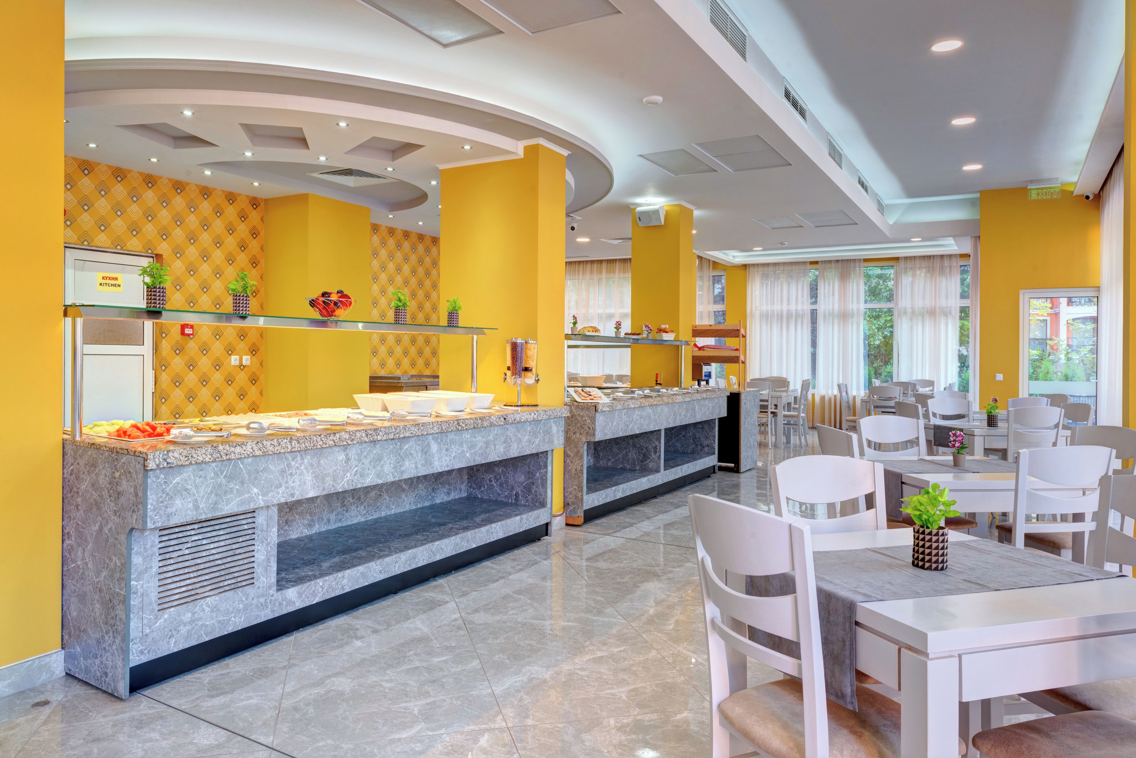 Een moderne hotellobby met een buffetgedeelte, zithoekjes en een receptiebalie.