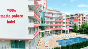 A multi-story hotel with balconies, a swimming pool, and a garden area.