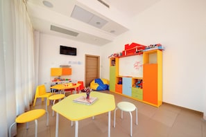A children's playroom with tables, chairs, a bean bag, and a whiteboard. - Maria Palace (Nessebar)