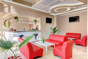 A lobby with red seating, a coffee machine, and a bar area labeled "Lobby Bar".