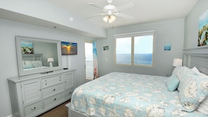 A bedroom with a bed, dresser, and a ceiling fan.