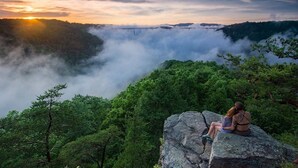 A couple sitting on a rock overlooking a forested valley with a bridge in the distance. - Romantic Get-away Cabin in the woods, w/Hottub next to coolest small town in USA (Victor)