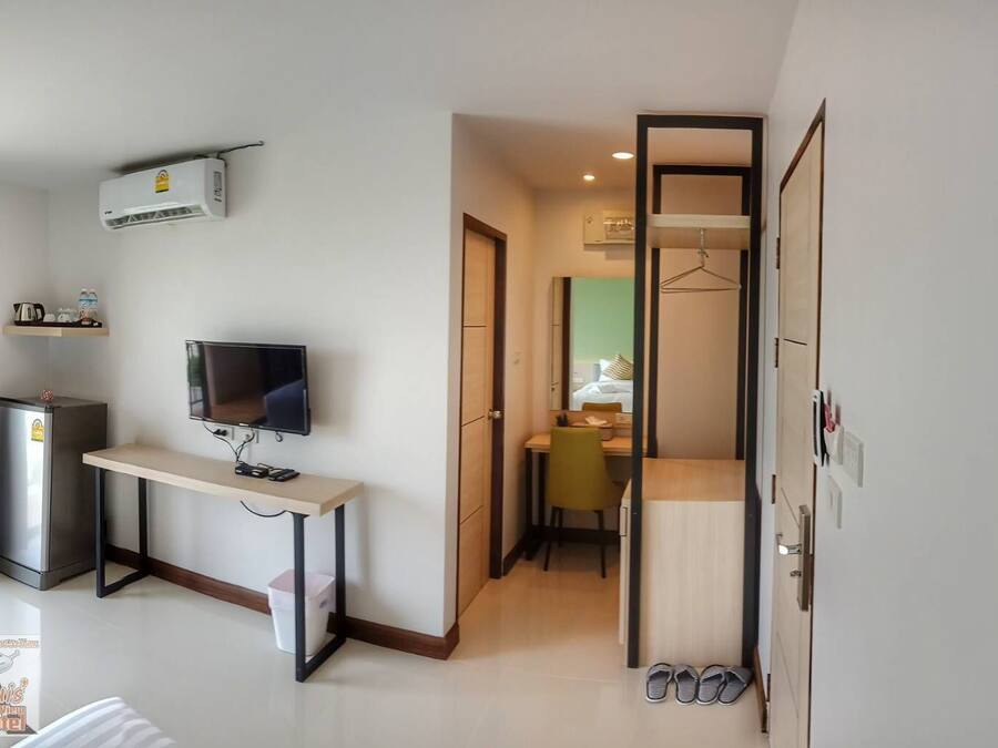 A hotel room with a desk, TV, air conditioning unit, and a wardrobe.