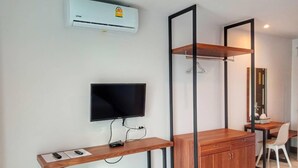 A modern hotel room with a flat-screen TV, wooden desk, wardrobe, and a mirror. - Louis' Runway View Hotel (Mai Khao)