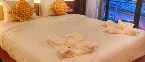 A neatly made bed with patterned pillows and towels arranged on the bed.