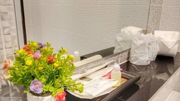 Un baño con planta en maceta, artículos de tocador y un espejo.