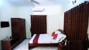 A bedroom with a bed, a wardrobe, a TV, and an air conditioning unit. - Novem Inn & Holidays (Sylhet)