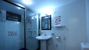 A bathroom with a glass shower enclosure, a white sink, a mirror, and a toilet. - Novem Inn & Holidays (Sylhet)