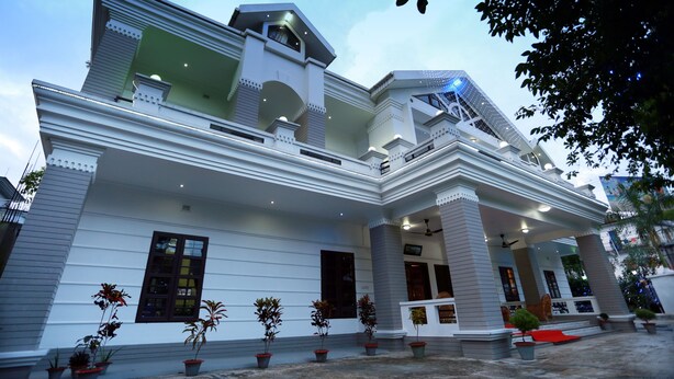 A large, two-story building with a symmetrical facade, multiple windows, and a central entrance. - Novem Inn & Holidays (Sylhet)