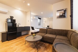 A compact living space with a kitchenette, a sofa, a dining table, and a bed.