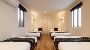 A hotel room with two beds, a wooden floor, a door, and two windows with curtains. - Grand Base Nagasaki (Nagasaki)