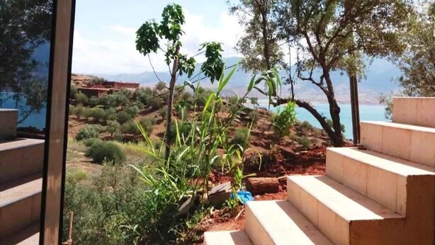 A view from a covered outdoor area with steps leading down to a garden. - Nice apartment by the lake 4579 (Bin El Ouidane)