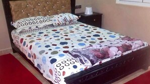 A bed with a polka dot bedspread, a floral pillow, and a wooden headboard. - Nice apartment by the lake 4579 (Bin El Ouidane)