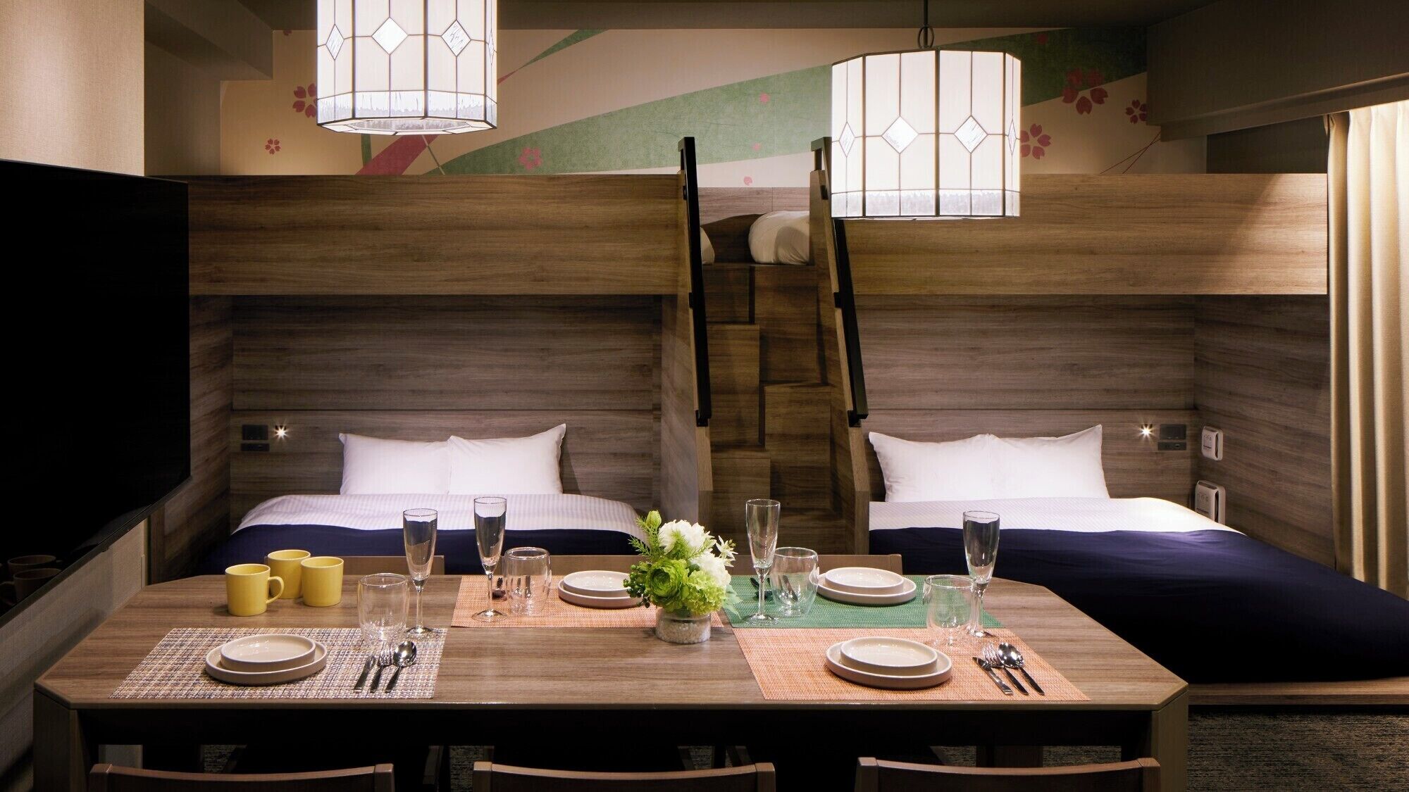 A hotel room with two beds, a dining table set for four, and a staircase connecting the two levels.