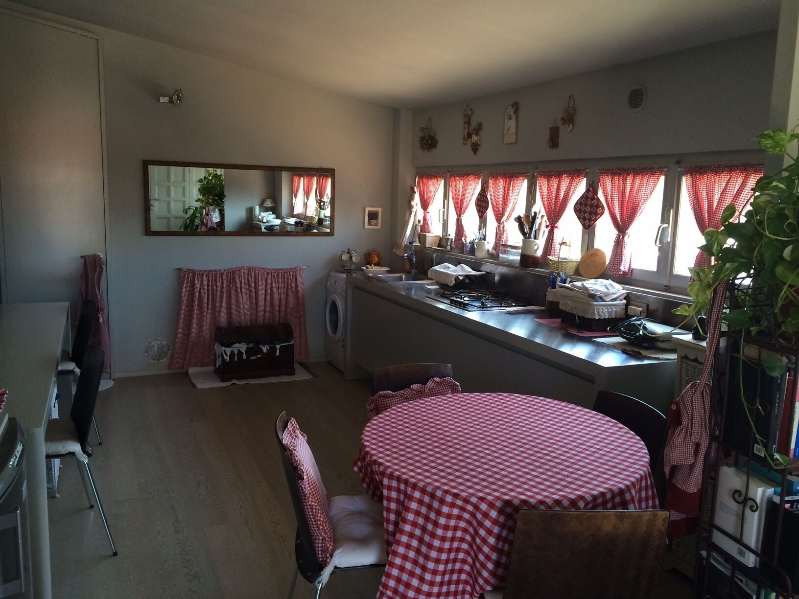 A compact kitchen with a dining area, featuring a round table with a checkered tablecloth, a washing machine, and a stove.
