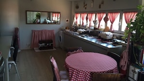 A compact kitchen with a dining area, featuring a round table with a checkered tablecloth, a washing machine, and a stove. - Rinidia Siena Celso Cittadini (Siena)