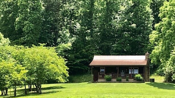 A rustic cabin with a porch, surrounded by lush greenery and trees. - Workman's Wildlife Haven, Secluded country setting vacation cabin (Louisa)