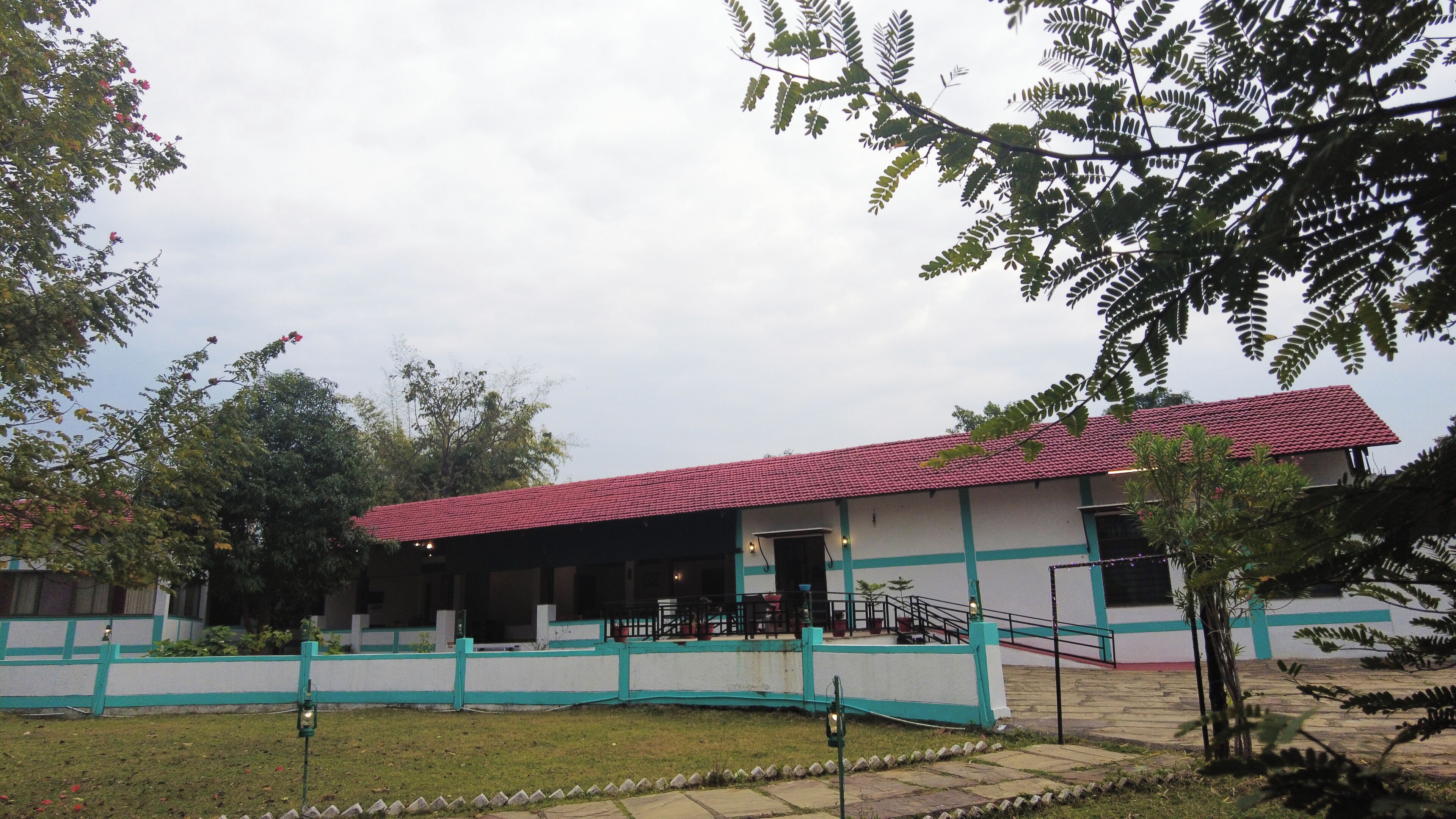 A building with a red-tiled roof, a covered outdoor seating area, and a white and teal exterior.