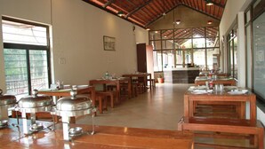 A spacious dining area with high ceilings and large windows, featuring multiple tables and buffet stations. - Nature's Sprout Wildmark Kanha Resort (Bichhiya)