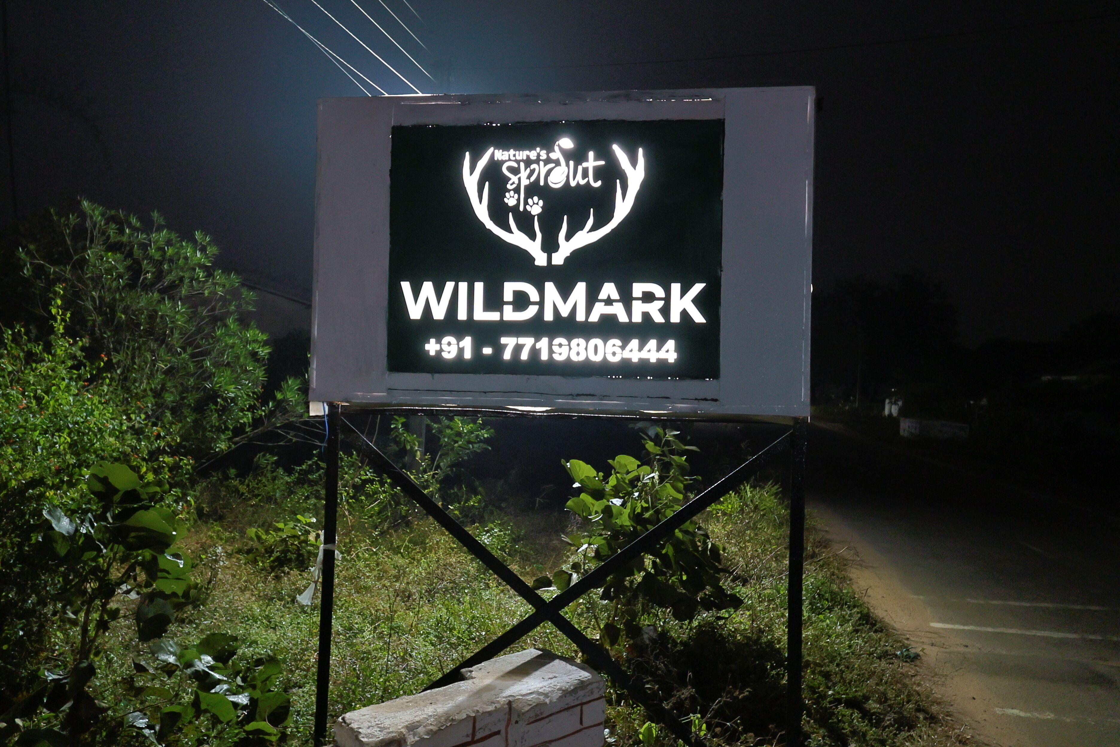 A billboard with the text "Nature's Sprout WILDMARK +91-7719806444".