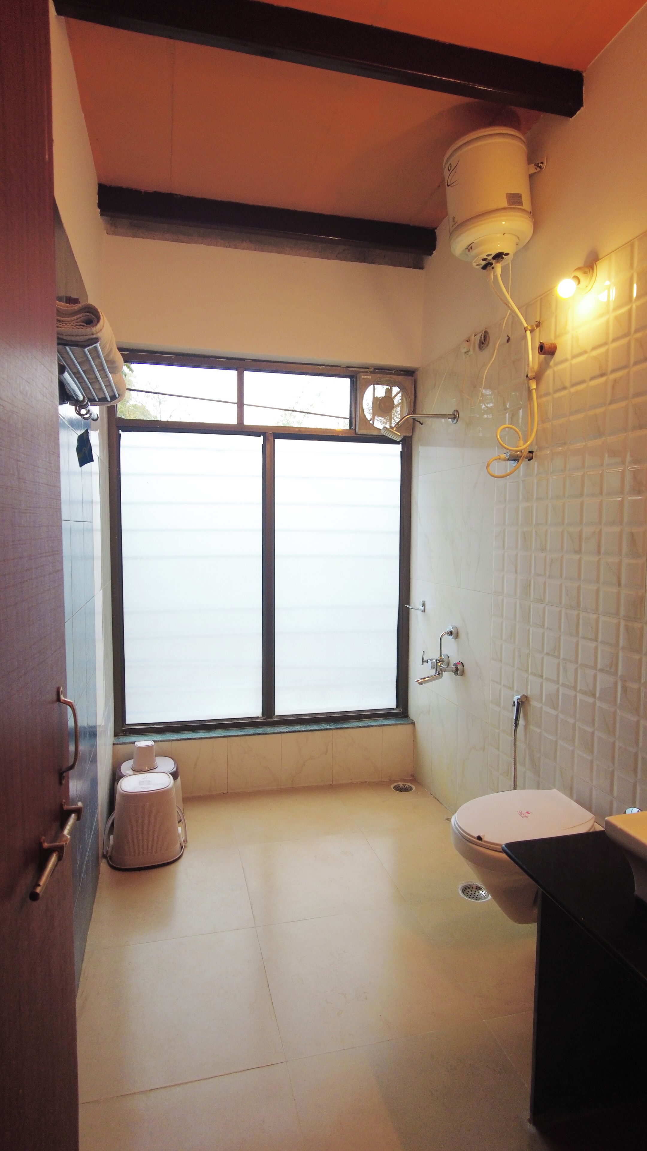 A bathroom with a toilet, bidet, and a window.