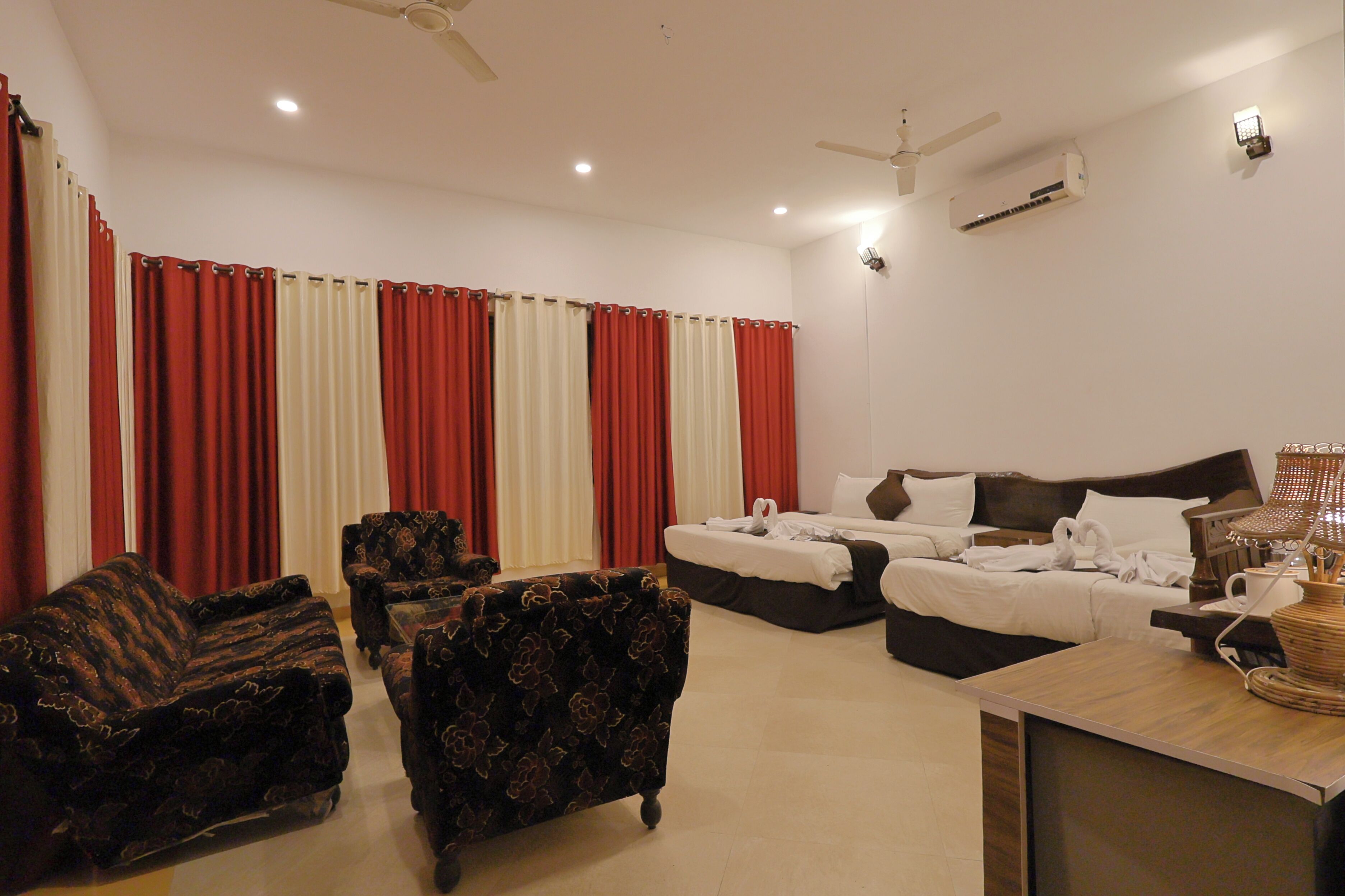 A hotel room with a bed, two sofas, a coffee table, and curtains.