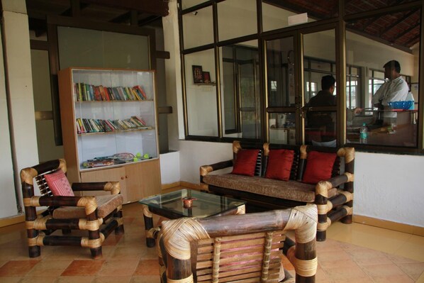Una habitación con un sofá de ratán, una mesa de centro de vidrio y una estantería.