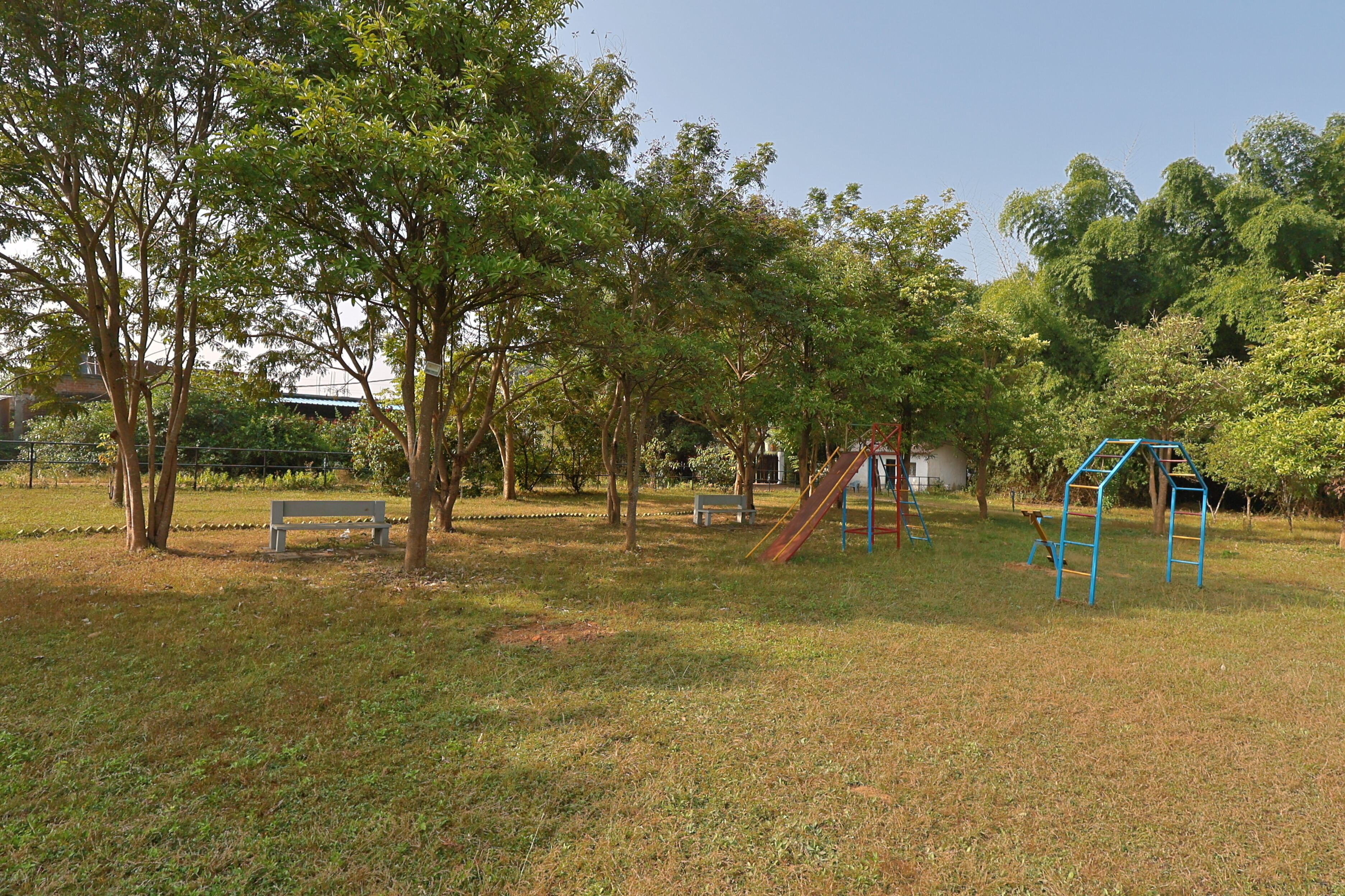 A park with playground equipment, benches, and trees.