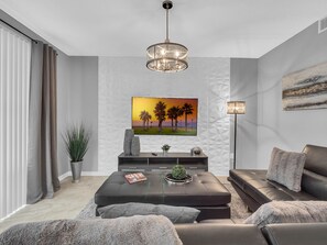 Relax in this stylish living room with a large flat-screen TV, comfortable seating area, and a floor lamp.