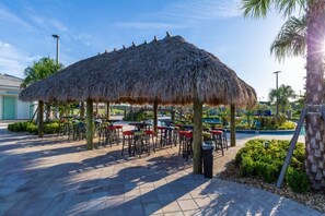 Relax in a shaded seating area surrounded by lush greenery and a nearby pool.