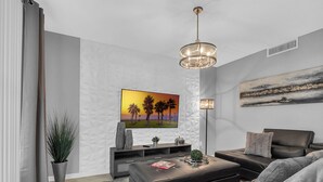 A modern living room with a flat-screen TV, a sofa, a coffee table, and a floor lamp.