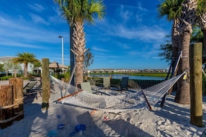 Relax in a serene hammock amidst a tranquil waterway, surrounded by a well-manicured lawn and a picturesque bridge.
