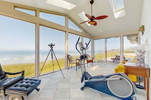 Relax in a spacious room with expansive views of the surrounding landscape, featuring a comfortable seating area and a dedicated workout space.