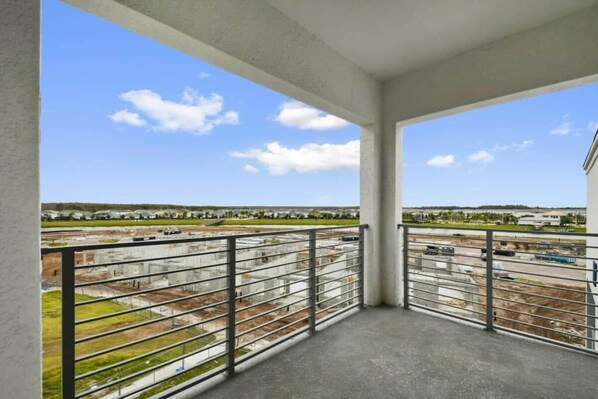 Un balcon donnant sur un chantier de construction et sur des bâtiments situés au loin.