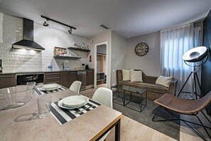A modern kitchen with a dining area, a sofa, and a clock on the wall.