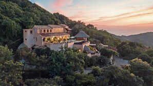 A hillside villa with multiple buildings, outdoor seating areas, and a pool. - Casa Angelina (Zihuatanejo)