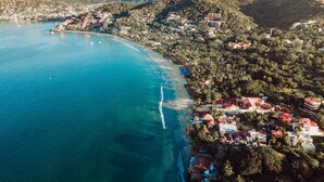 An aerial view of a coastal town with a beach, houses, and hills in the background. - Casa Angelina (Zihuatanejo)