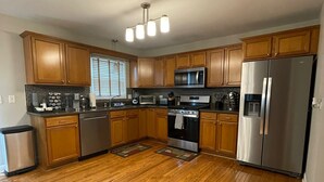 Une cuisine moderne avec des meubles en bois, des appareils électroménagers en acier inoxydable et un plancher en bois franc.