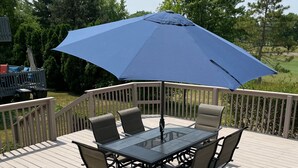 Une terrasse dotée d’une table et de chaises à plateau en verre, entourée d’une rambarde blanche.
