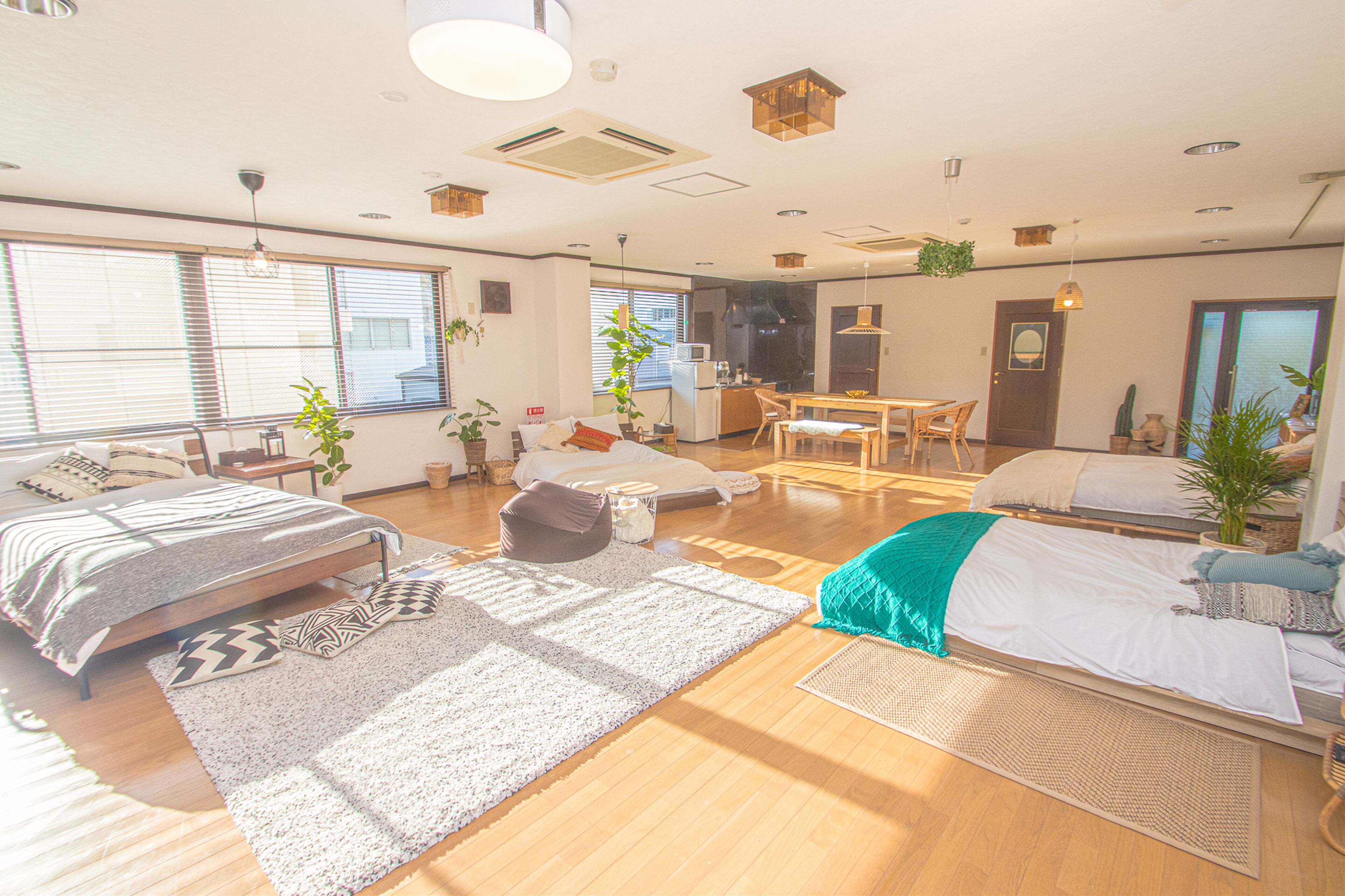 A spacious living area with a large bed, a dining table, and a kitchen in the background.