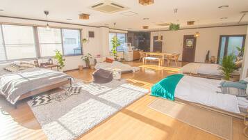 A spacious living area with a large bed, a dining table, and a kitchen in the background.